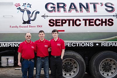 The Grant’s standing next to a pumping truck with their logo on it.